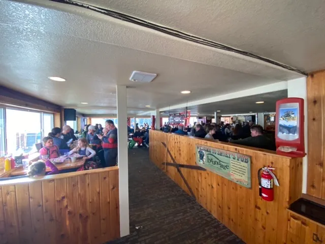 Crowded ski lodge cafeteria with a wood counter and windows