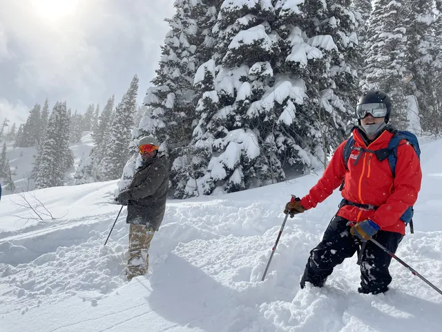 Two skiers in deep powder posing among snowy trees at Brundage Mountain
