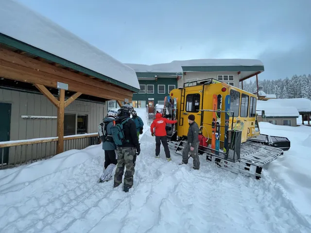 Skiers and the yellow snowcat parked outside the lodge after fresh snow