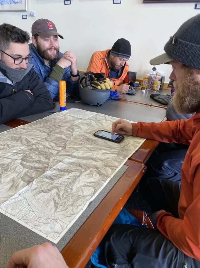 Group looking over a topographic map and phone at a table